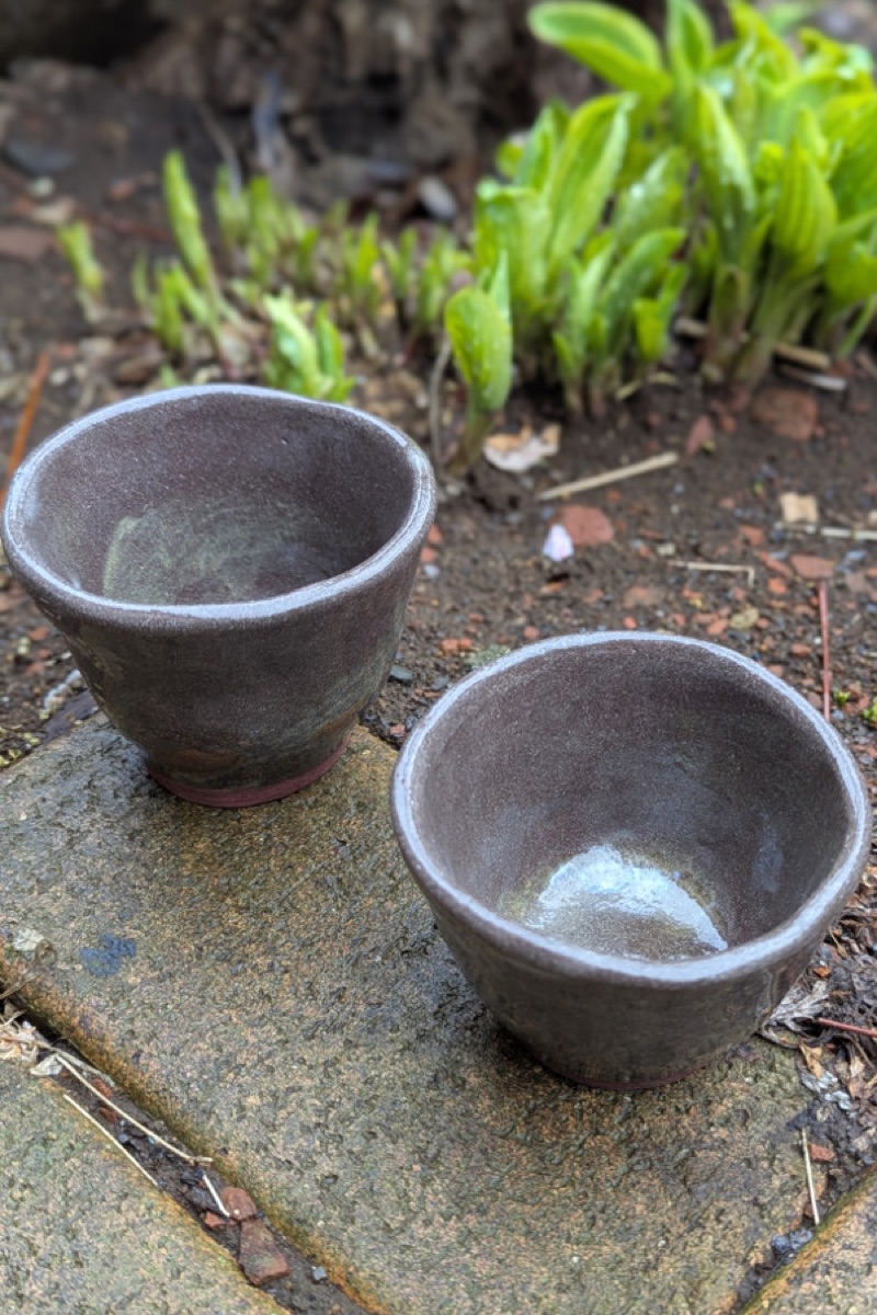 石の上に並んだ焦げ茶色の湯のみ